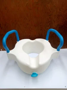 White raised toilet seat with padded armrests securely attached to a standard toilet for safe sitting and standing.